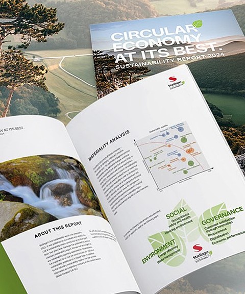 The image shows the opened 2024 sustainability report of Starlinger & Co Ges.m.b.H. In the foreground, an open double-page of the report displays a materiality analysis and the three key CSR categories: "Social," "Environment," and "Governance" in a graphic. In the background, there is a landscape with gentle, green hills covered in a light mist. A closed copy of the report is placed over the landscape, with the title "Circular Economy at its Best – Sustainability Report 2024" visible on the cover.